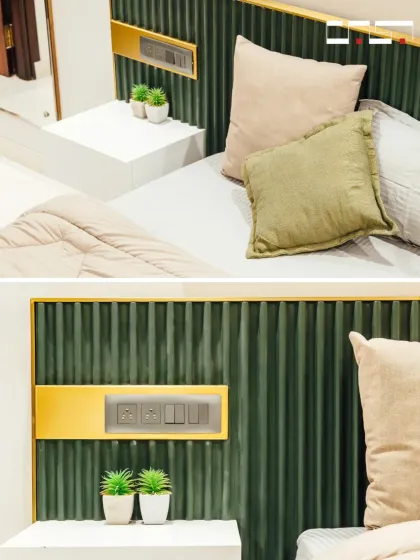 This image highlights the detail of the custom headboard, which integrates a sleek gold-finished panel with switches and outlets for ultimate convenience and a touch of luxury.