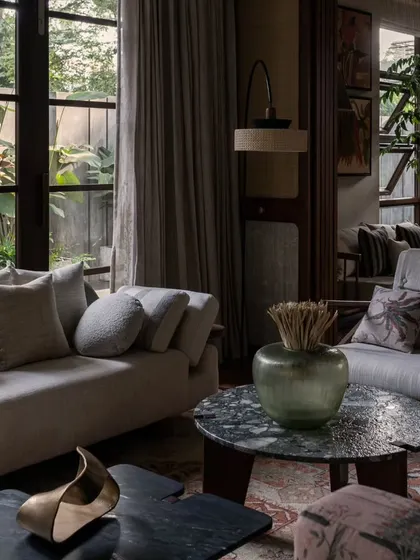 A close-up of the living room seating, showing the layering of cushions and the unique forms of the coffee tables. Every piece is chosen to contribute to the overall narrative of a comfortable, artful home.