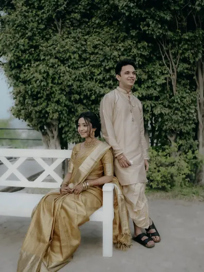 An elegant, posed portrait of the couple on a white bench, showcasing their classic and coordinated engagement outfits.