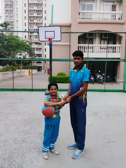 A young player proudly holds his trophy and basketball after a successful Ranking Day.