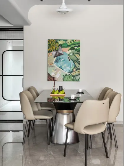 In this dining area, the design is intentionally simple to let food and conversation be the focus. The sleek table and neutral chairs are set against a clean canvas, punctuated by a single piece of art.