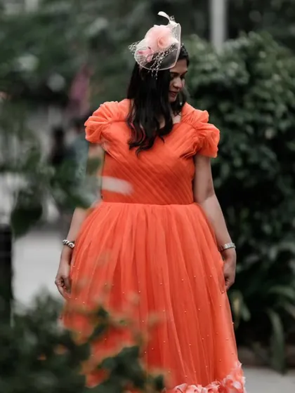 The vibrant orange gown is a go-to color for this party season. Paired with a delicate fascinator, it creates a chic and sophisticated look for any event.