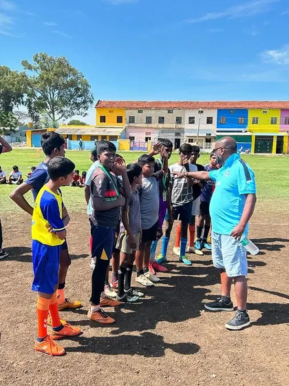 A coach gives a pre-game talk to his team at the KGF Champion Grounds. A moment of focus and strategy before the action begins.