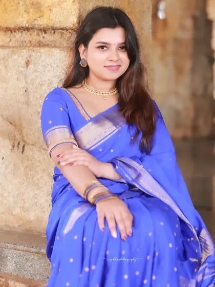 Portraits of a model in a vibrant blue saree, shot within the historic and atmospheric corridors of a temple. The stone pillars and natural light create a dramatic and timeless setting.
