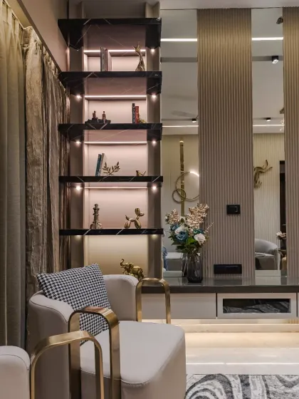 A perfect blend of modern luxury and artistic refinement. This living space features a sculptural accent chair with gold metallic arms and sleek, marble-detailed shelving with integrated lighting. Every detail is curated to enhance depth, warmth, and timeless charm.