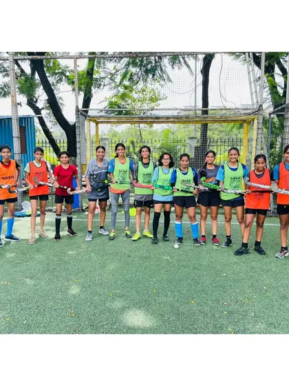 Another angle of our dedicated girls' team, standing with their coach before a practice session. Their commitment to the sport is evident.