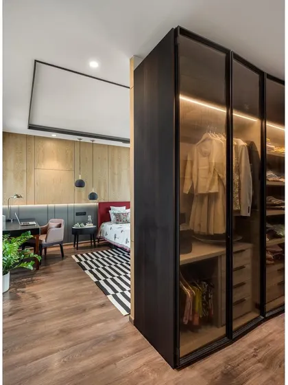 The walk-in wardrobe in apartment 5212, with its smoked glass doors and integrated lighting, acts as a screen to create a private dressing area.
