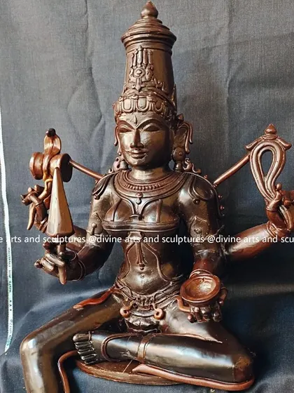 This wax model shows Mariamman, the South Indian mother goddess of rain and fertility. Her form is sculpted with traditional iconography, including the damaru (drum) and trident.