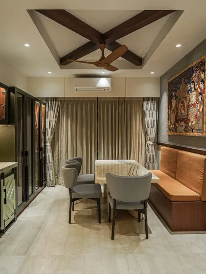 A dining area with bench seating, where a Pattachitra painting hangs above, blending farmhouse charm with Indian art.