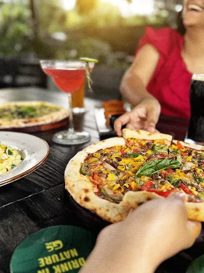 Grabbing a slice of pizza to share. Our large tables are perfect for group gatherings.