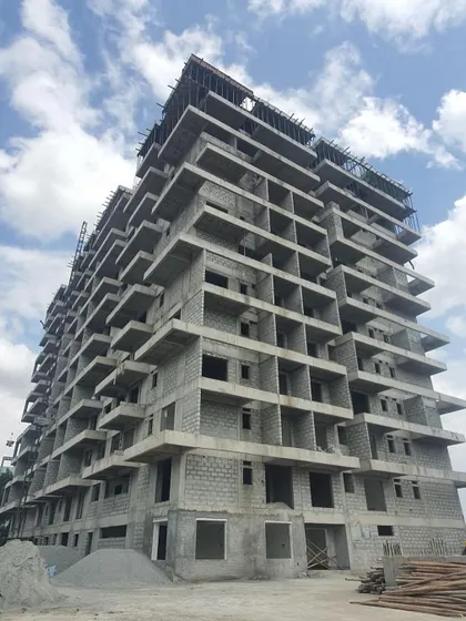The building's structure seen from the ground level, with piles of construction materials ready for use. This is where the architectural plans begin to become a physical reality.