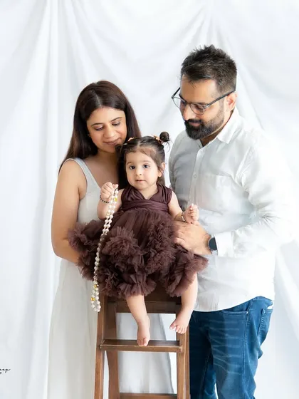 A simple and sweet family portrait against a clean white background. The focus is entirely on the family's connection and their adorable baby girl.