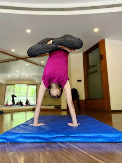 Turning things upside down to see if they look any better. This student practices a lotus headstand, a pose that challenges balance and hip flexibility.