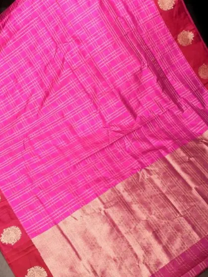 A bright pink checked silk saree with a rich red border. The gold buttas on the border add a touch of traditional opulence.