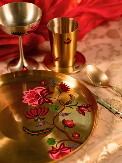 A close-up of the exquisite hand-painted Kansa tableware used for the festive dinner setting.