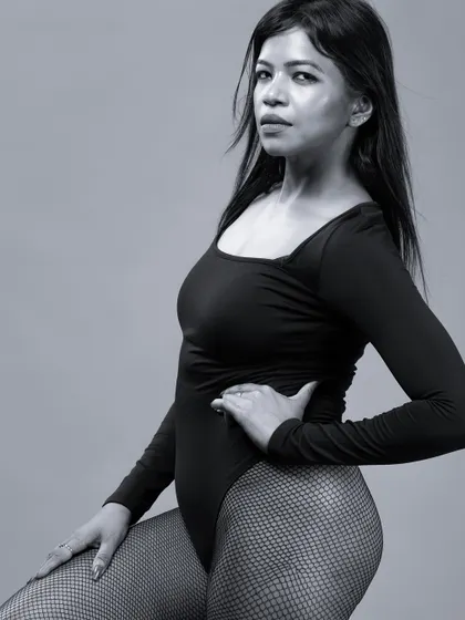 A closer-in black and white shot of the model in the bodysuit, focusing on her direct gaze and confident pose.