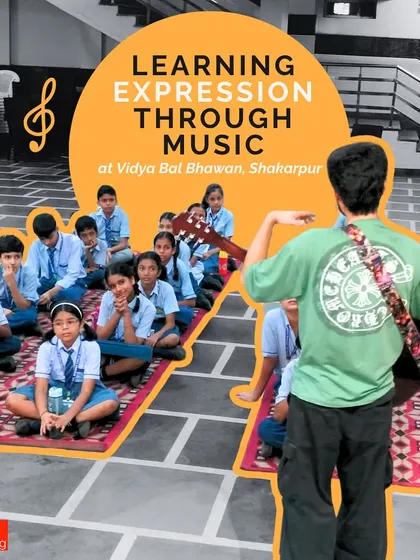 Learning expression through music is at the heart of what we do. An instructor with a guitar guides a group of students sitting on the floor, creating an intimate and focused learning environment.