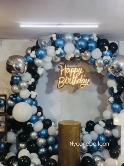A classic ring decoration for a first birthday party. The blue, black, silver, and white balloons create a stylish look, complemented by a light-up number '1' and transparent letter blocks.