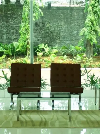 A lounge area at TCS Yantra Park, with full-height glass walls looking out onto a dense green buffer. The design ensures that even within a bustling IT campus, there are moments of quiet connection with nature.