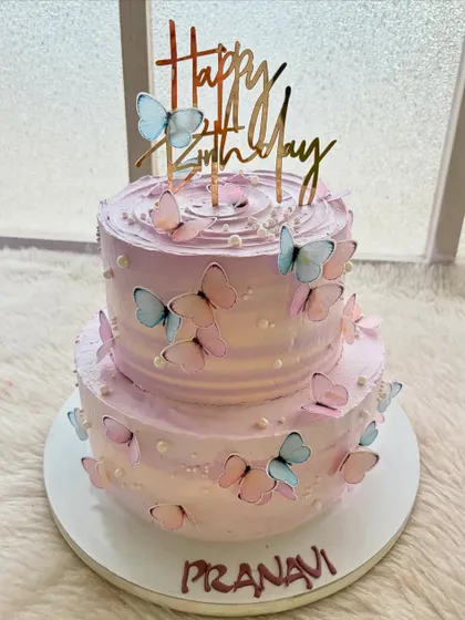 A dreamy two-tier cake in shades of lavender, covered in delicate, fluttering butterflies. This is a beautiful and whimsical design for a birthday.