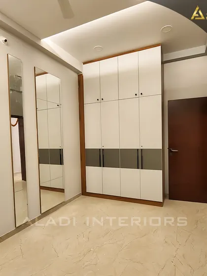 A floor-to-ceiling wardrobe in a minimalist design, featuring white and grey panels. The full-length mirrors on the side add functionality and make the room feel larger.