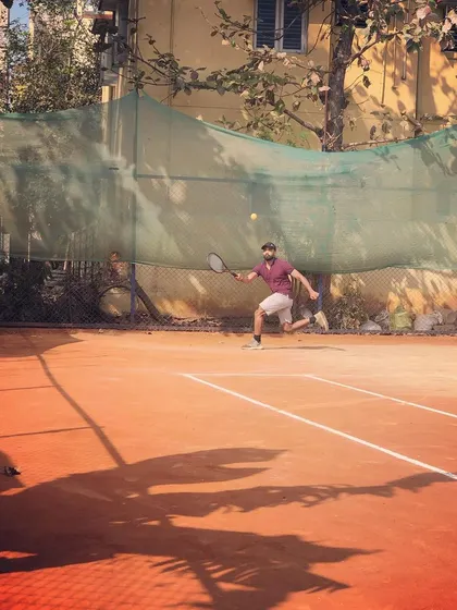 An adult male player stretches for a forehand shot during a competitive match in the Men's Open Tour.