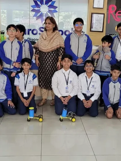 Students and a teacher from Euro International School pose with the floor-cleaning robots they built during our hands-on workshop.
