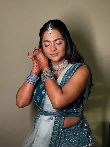 The final touch. This candid shot captures the bride putting on her earrings, with her glowing makeup and henna-adorned hands creating a beautiful composition.