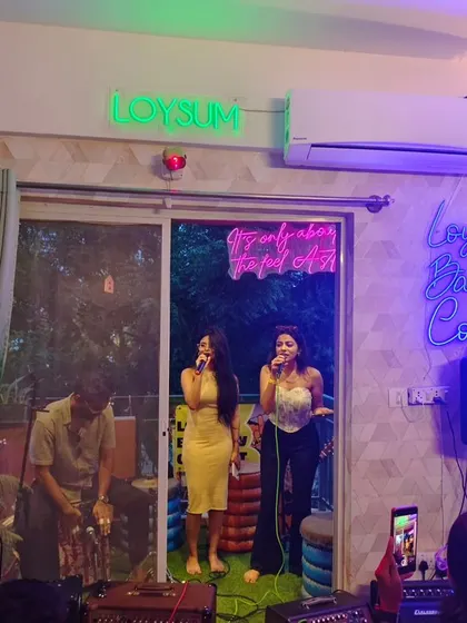A shot of the artists and the setup during a Loysum Balcony Concert. The neon signs, the cozy seating, and the open balcony create a unique stage for our intimate musical gatherings.