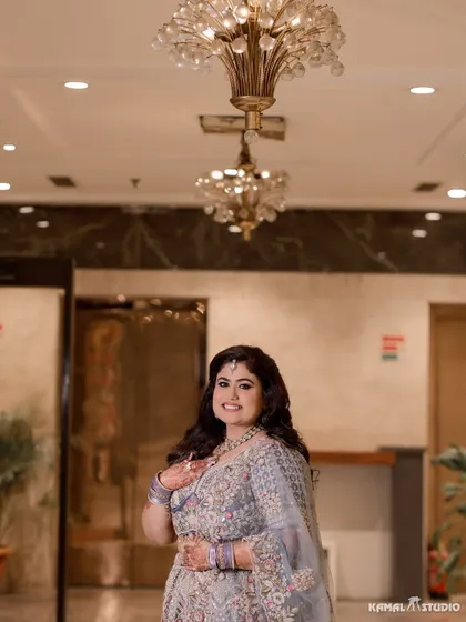 A joyful portrait of the bride at her Roka ceremony, captured under the warm light of a chandelier.