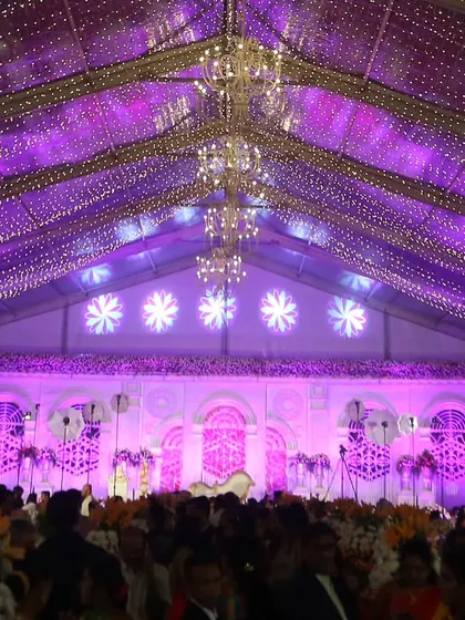 For a truly grand affair, we transformed this large tented venue with a ceiling of cascading fairy lights and magnificent chandeliers. The purple uplighting and expansive stage create a sense of awe and splendor.