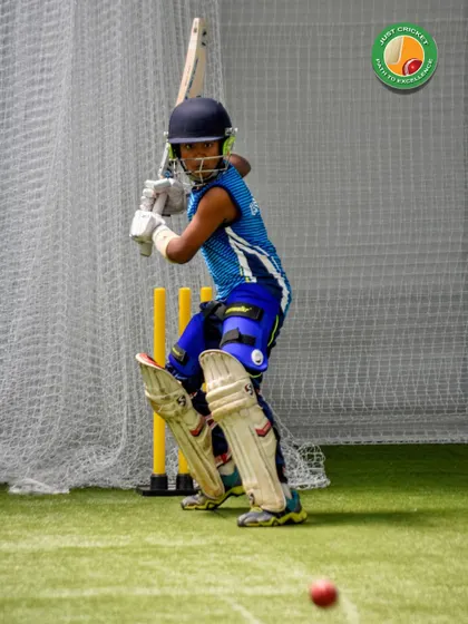 Eyes on the prize. A young batsman in the nets, fully focused on the incoming ball, ready to play his shot.