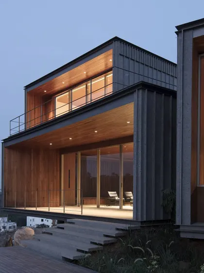 Exterior lighting is used to highlight the architectural form and warm wood textures of the structure. The design ensures the home has a soft, welcoming presence on the hillside after dark.
