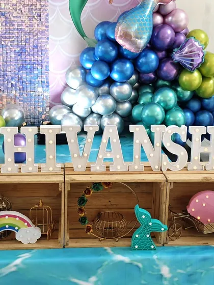 Marquee letter's spelling 'SHIVANSHI' are placed in front of wooden crates for a rustic-meets-magical look.