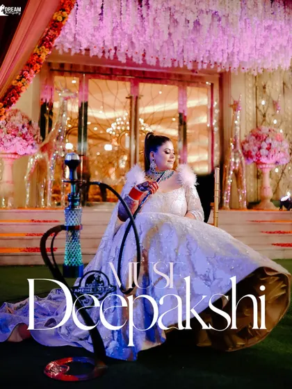 A regal portrait of the bride Deepakshi, seated gracefully in her elaborate gown next to a modern hookah, blending tradition with contemporary style.
