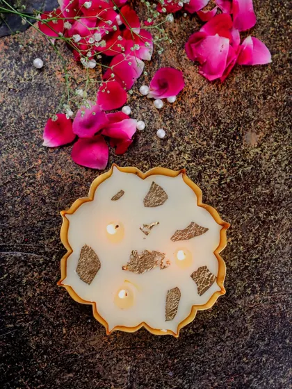 A lit mini gold Urli candle, its multiple wicks creating a beautiful, warm glow.