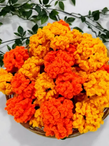 A basket full of bright orange and yellow crochet marigolds from a recent bulk order. Each one is handmade by me and ready to be used for decoration.