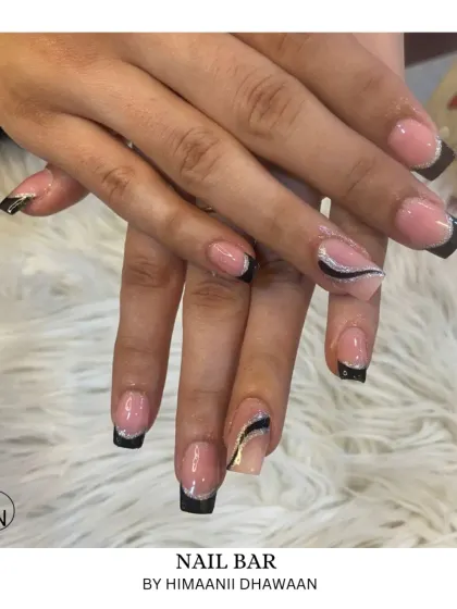 A modern take on the French manicure with sharp, graphic black tips and silver glitter accents.