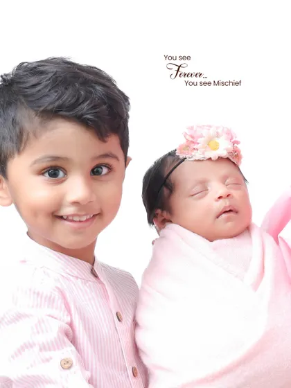 A proud big brother poses with his sleeping newborn sister. Sibling photos with a newborn require extra care and patience, which I always provide.