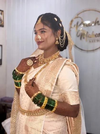 A beautiful Buddhist bride in a traditional white and gold saree, complete with green bangles and a Maharashtrian nath.