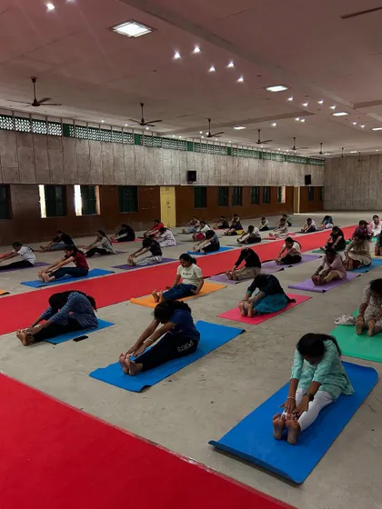 Students engaging in Paschimottanasana (Seated Forward Bend). This pose calms the brain, relieves stress, and provides a deep stretch for the entire back body.