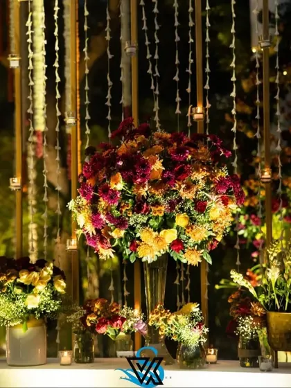 A stunning, large floral centerpiece set against a backdrop of hanging flower strings and candles. This shows how we layer different elements to create a rich, multi-dimensional look.