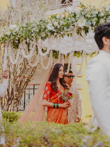 A beautiful shot of the bride making her way to the mandap. The soft, natural light highlights the rich color of her saree and her graceful posture.