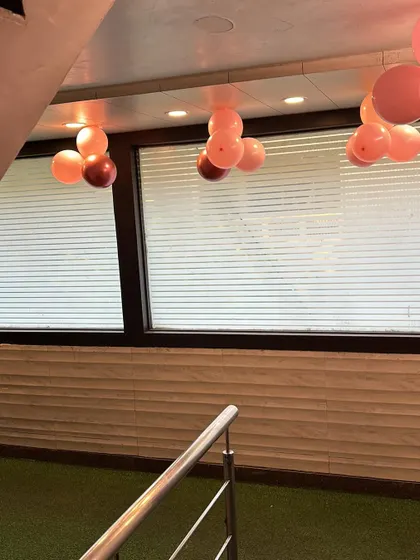 Part of an anniversary decor setup, showing simple balloon bunches hanging from the ceiling. These small details help fill the space and tie the whole look together.