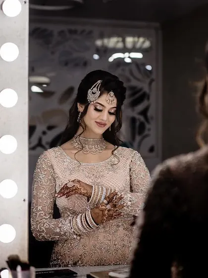 A behind the scenes moment of the bride getting ready. This mirror shot captures her final touches, surrounded by the soft glow of vanity lights, adding a touch of glamour.