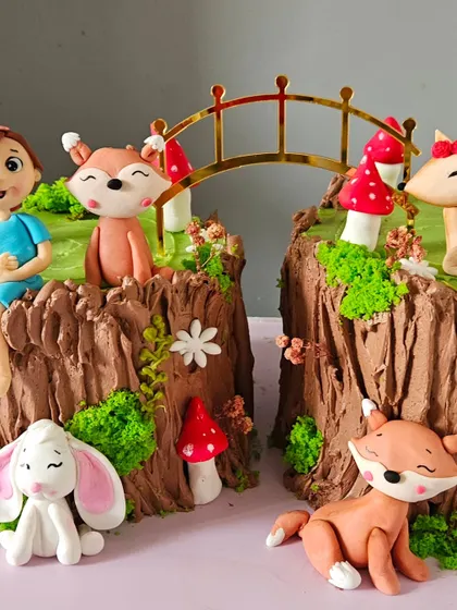 A detailed close-up of the enchanted forest cake, showing the expressive faces of the handmade fox and bunny figurines.