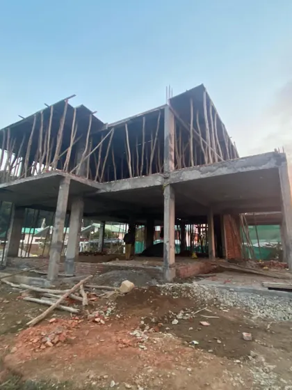 The concrete skeleton of a villa in Dehradun at sunset. The temporary wooden supports, or shuttering, are still in place for the upper floor slab.