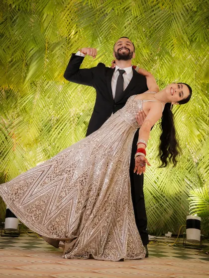 A dynamic and joyful shot of the groom dipping the bride during a dance, her sparkling gown catching the light beautifully.