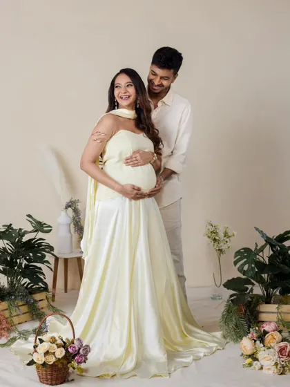 In our indoor garden setup, this couple shares a happy moment. The flowing dress and surrounding flowers add a soft, romantic feel to this studio maternity portrait.