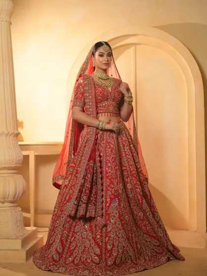 A full-length shot showcasing the magnificent red lehenga and the stunning bridal makeup. The look is cohesive, regal, and absolutely breathtaking.